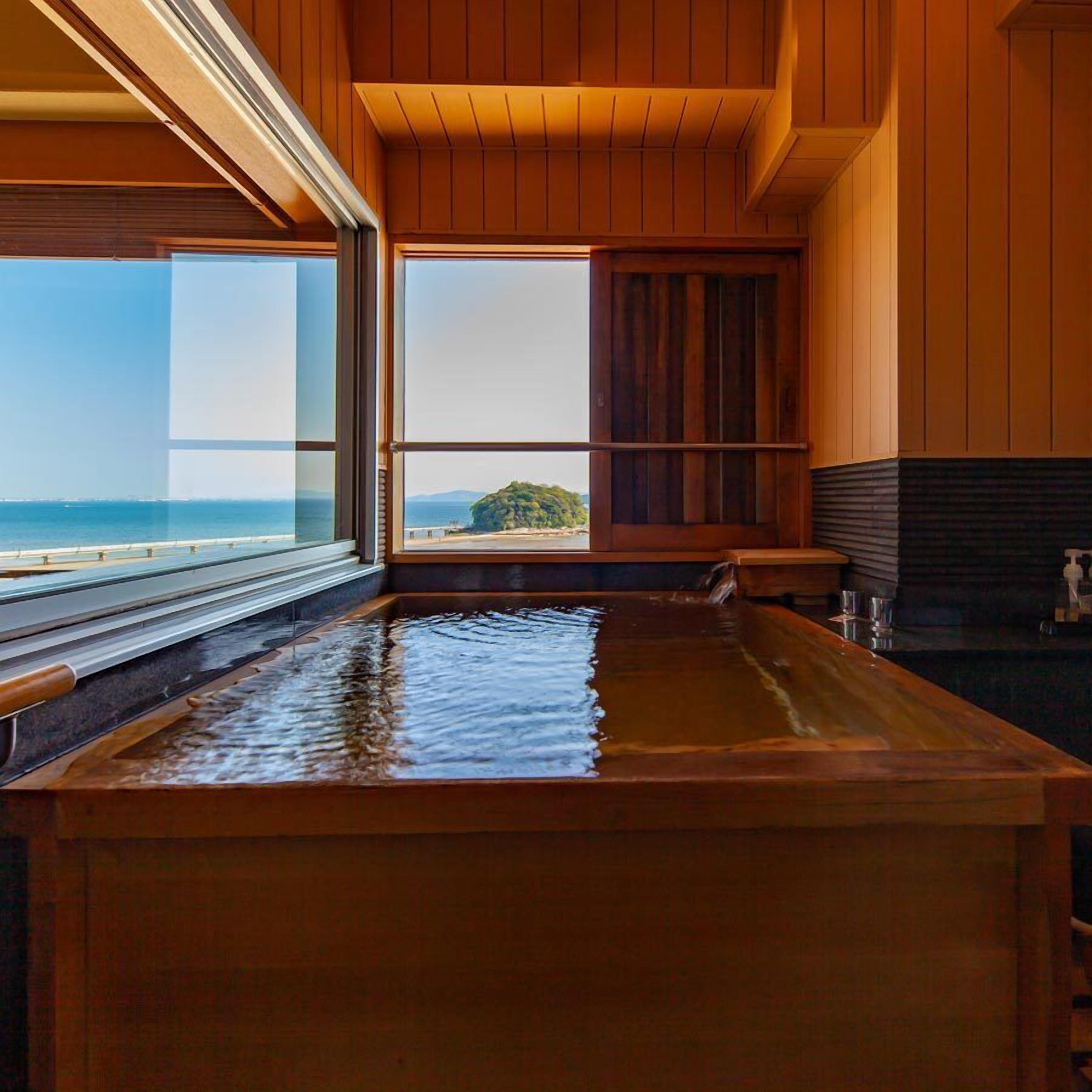 Un interior de madera con un amplio ventanal que ofrece vista al mar y una isla distante.