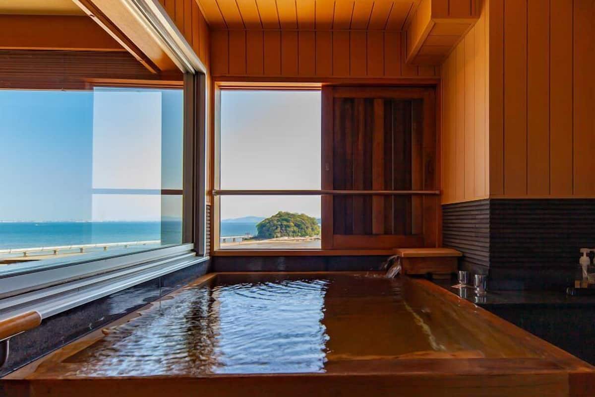Un interior de madera con un amplio ventanal que ofrece vista al mar y una isla distante.