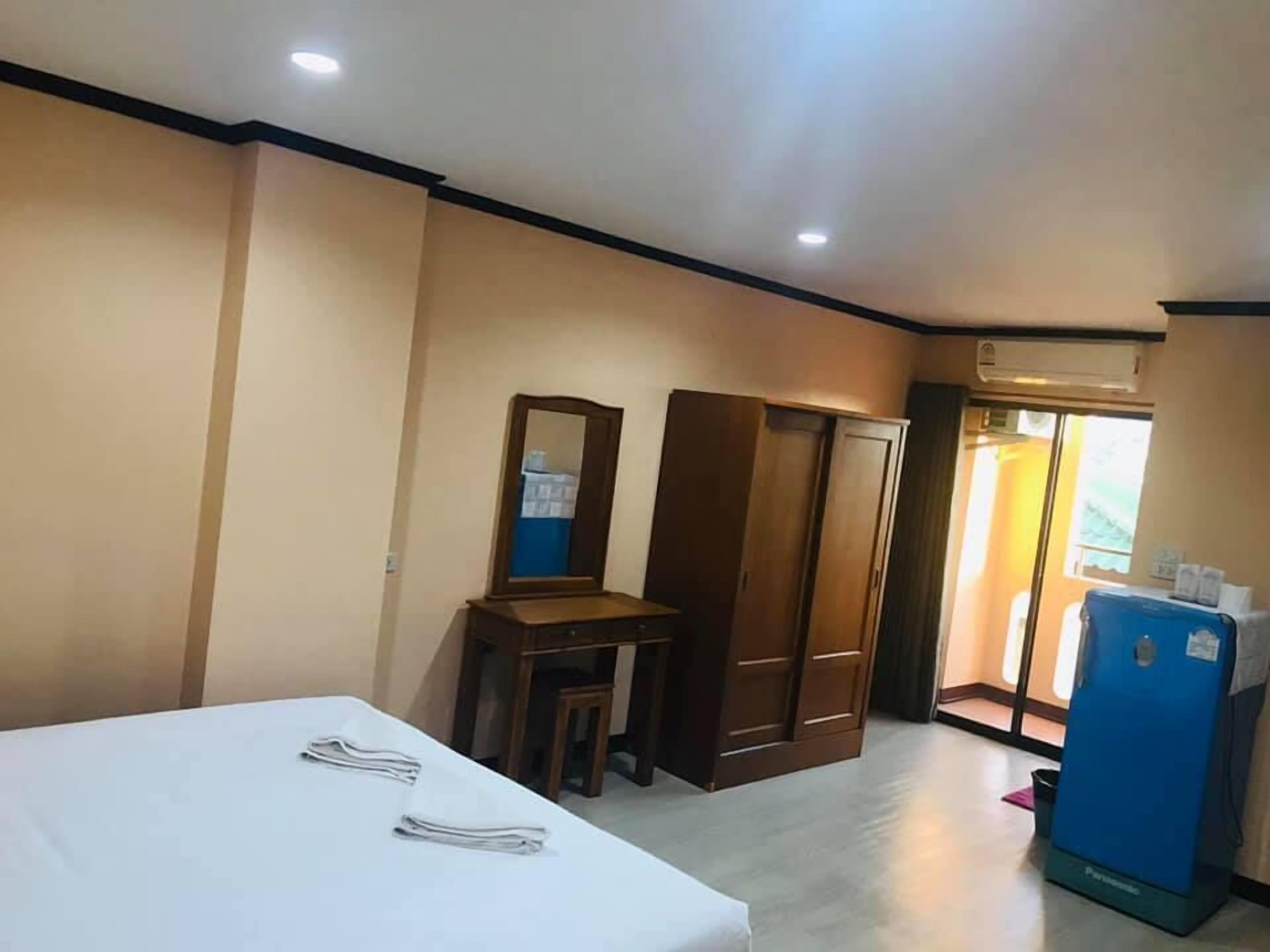 A hotel room with a bed, a desk with a mirror, a wardrobe, and a minibar.