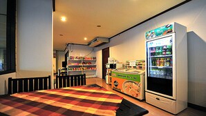 A room with a checkered floor, a vending machine, a microwave, and a refrigerator. - B.P Grand Service Apartment (Chiang Mai)