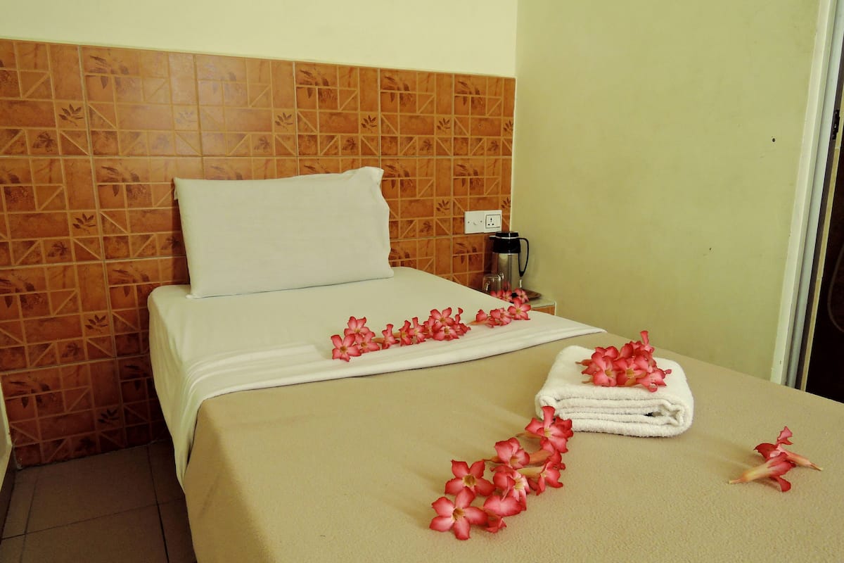 Una habitación de hotel con una cama, una cafetera y una toalla con flores sobre la cama.