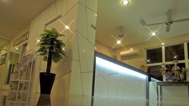 Eine moderne Lobby mit einer großen Kübelpflanze, einem spiegelnden Boden und einem hellen, geometrischen Wanddesign.