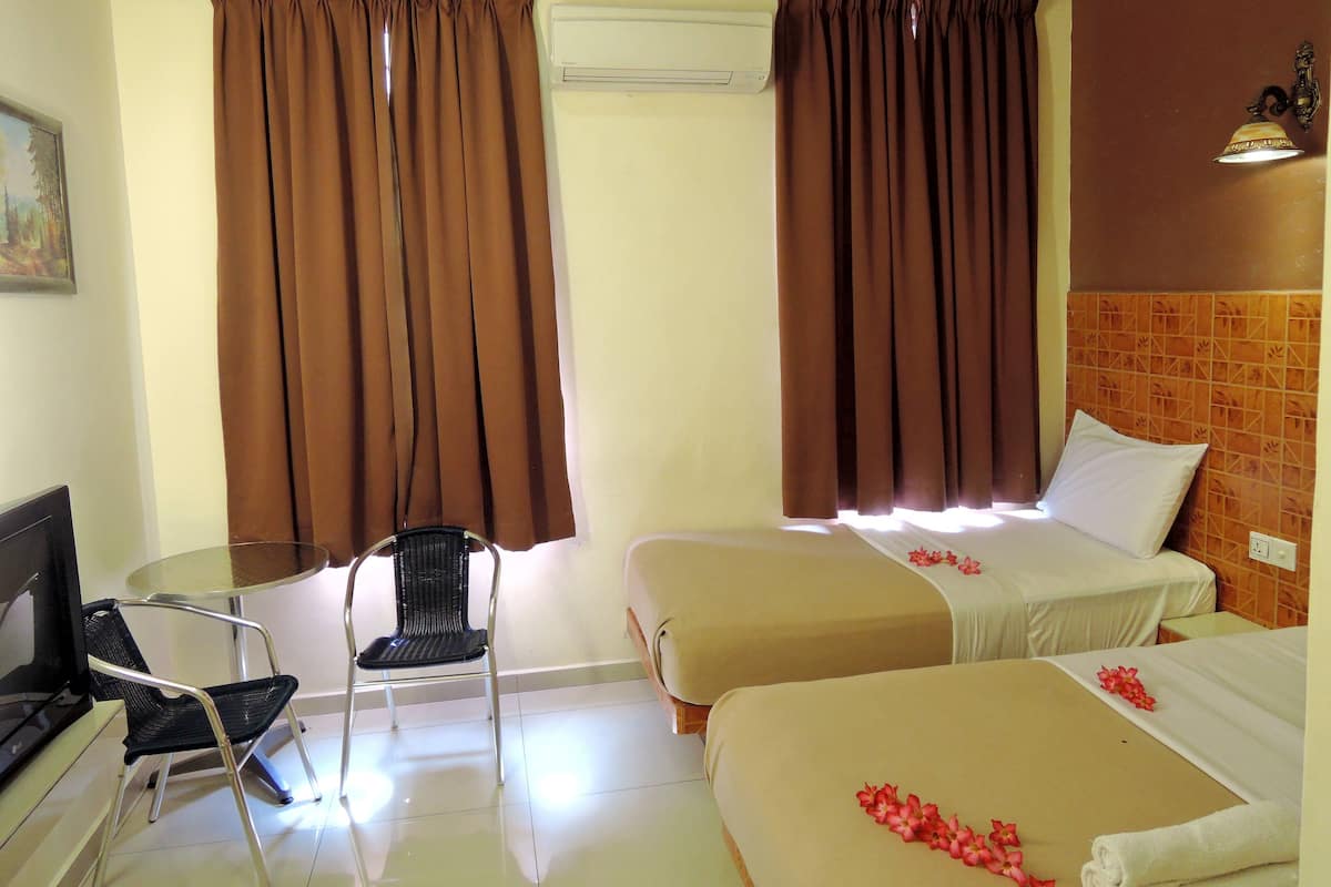 Una habitación de hotel con dos camas, un escritorio con una silla y un equipo de aire acondicionado.