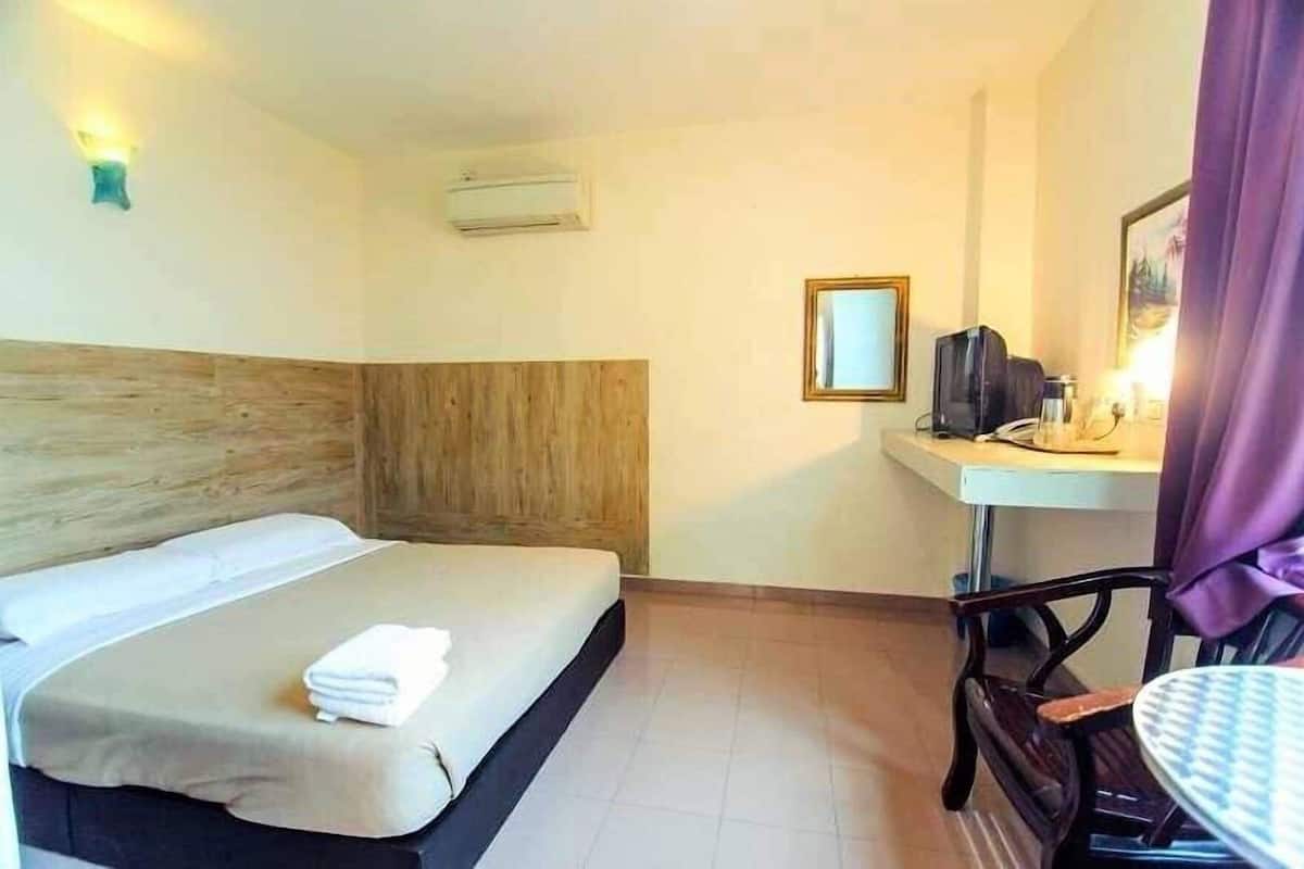 Habitación de hotel con cama, escritorio, silla, cafetera y una mesita.
