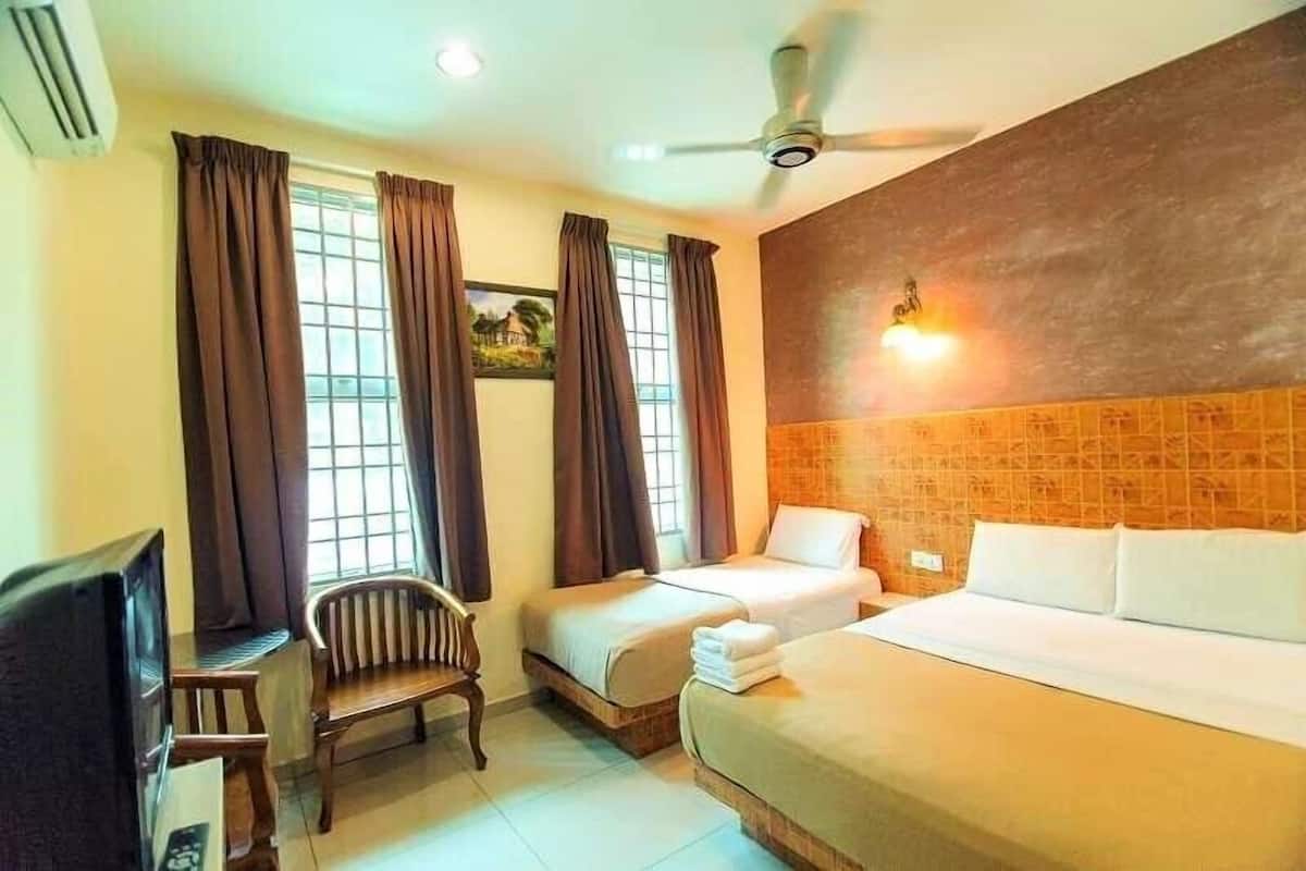 Habitación de hotel con dos camas, un escritorio, una silla, un televisor y un ventilador de techo.