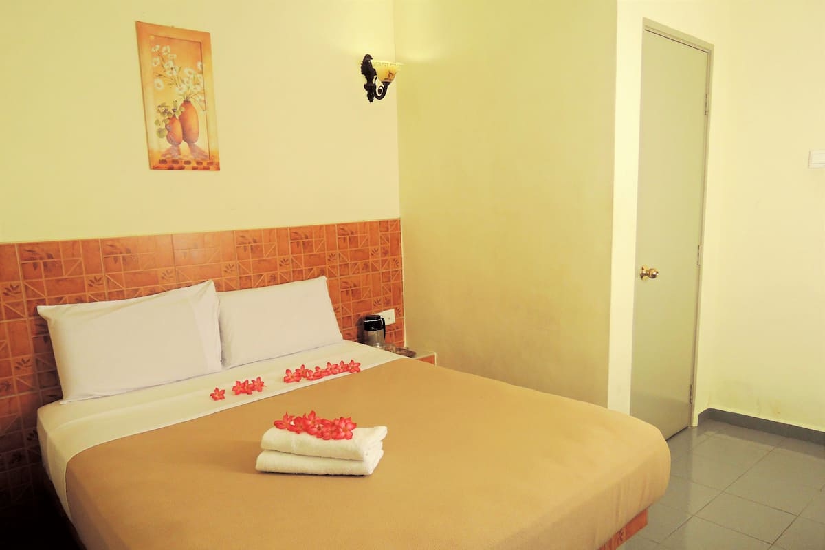 Una habitación de hotel con cama, mesita de noche, un cuadro en la pared y una puerta.