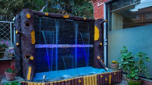 A wooden hot tub with a blue water feature, surrounded by potted plants and a metal fence. - The Boudha Inn (Kathmandu)