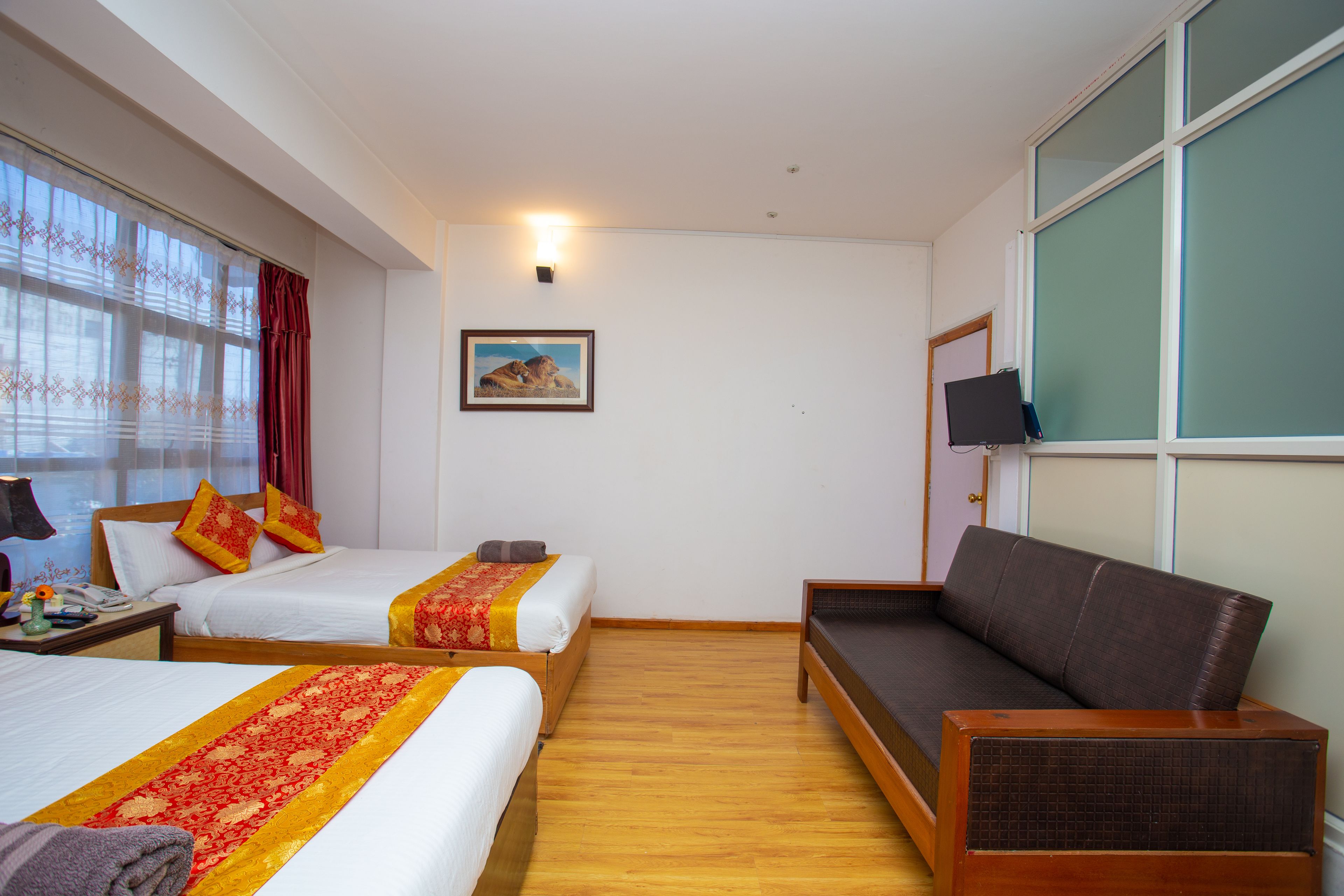 Ein Hotelzimmer mit zwei Betten, einem Sofa, einem Fernseher und einem Bild an der Wand.