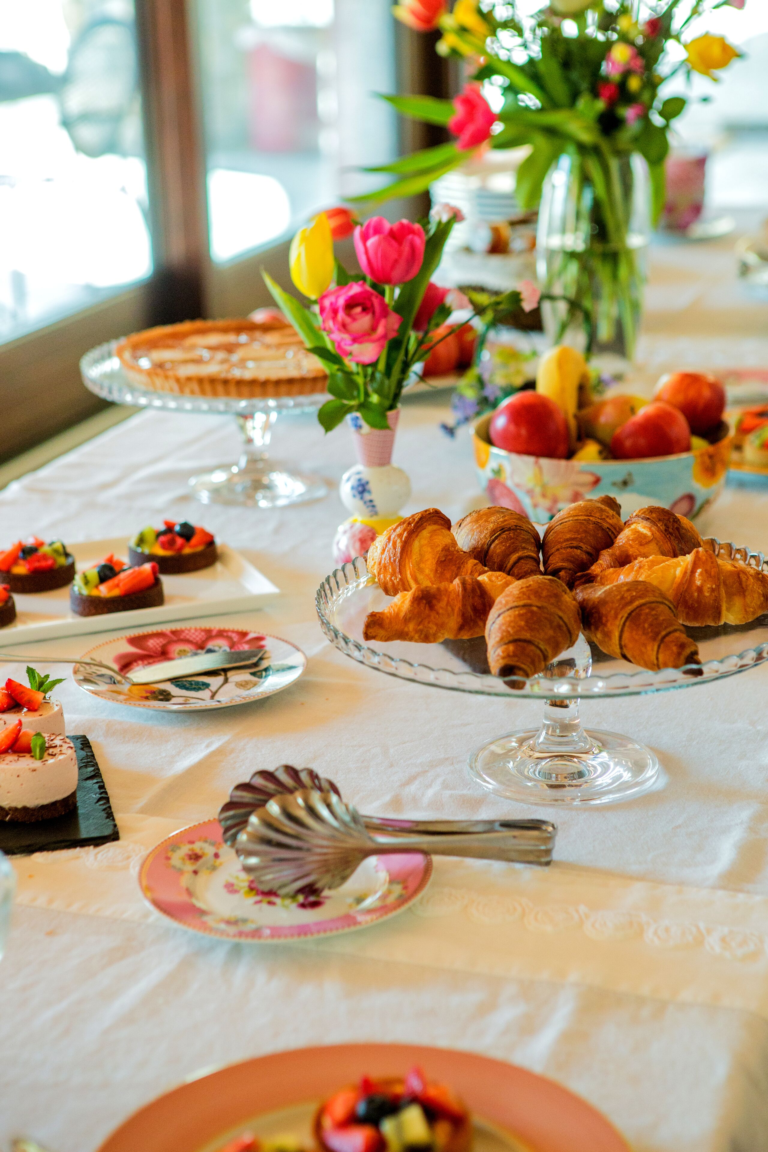 Una mesa servida con diversos alimentos, incluyendo pasteles, frutas y postres.