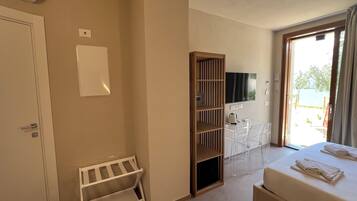 Habitación de hotel con cama, un escritorio pequeño con silla, televisor y ventana con cortinas.
