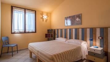A bedroom with a bed, a chair, a nightstand, a wall-mounted light, and a painting.
