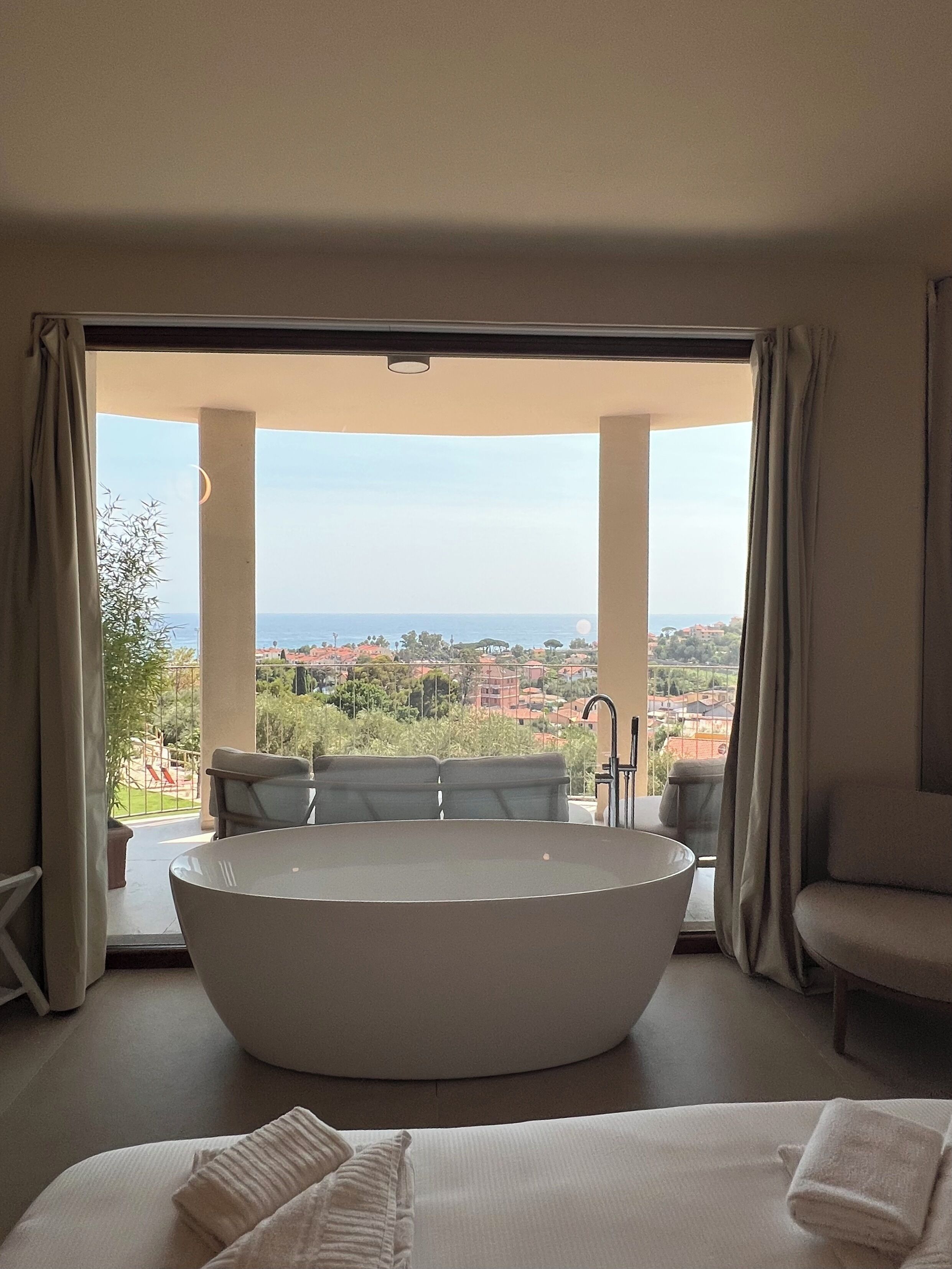 Une chambre moderne dotée d’une grande baignoire, d’un canapé et offrant une vue sur la ville et la mer.