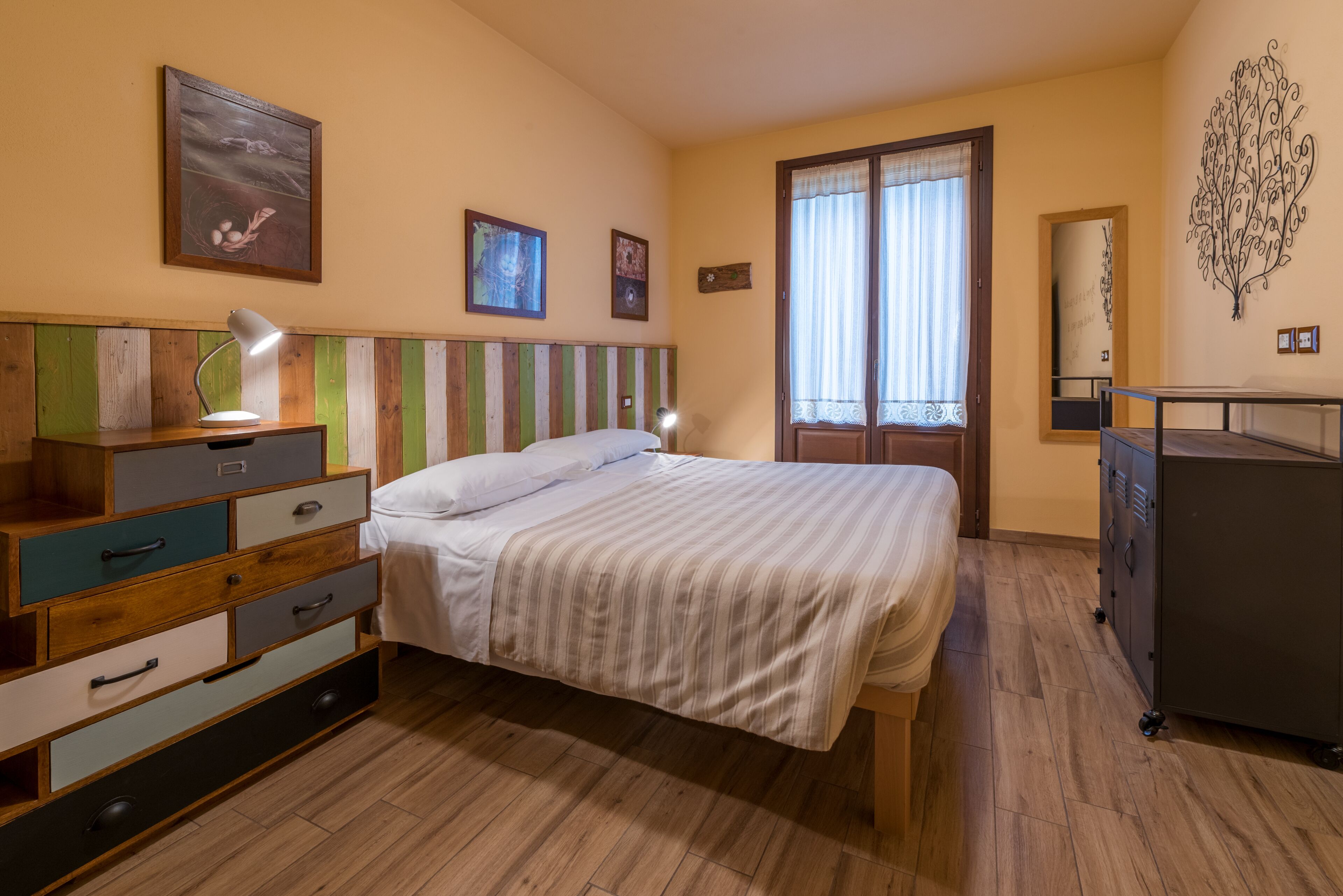 Un dormitorio con una cama, cómoda de madera y un escritorio con lámpara.