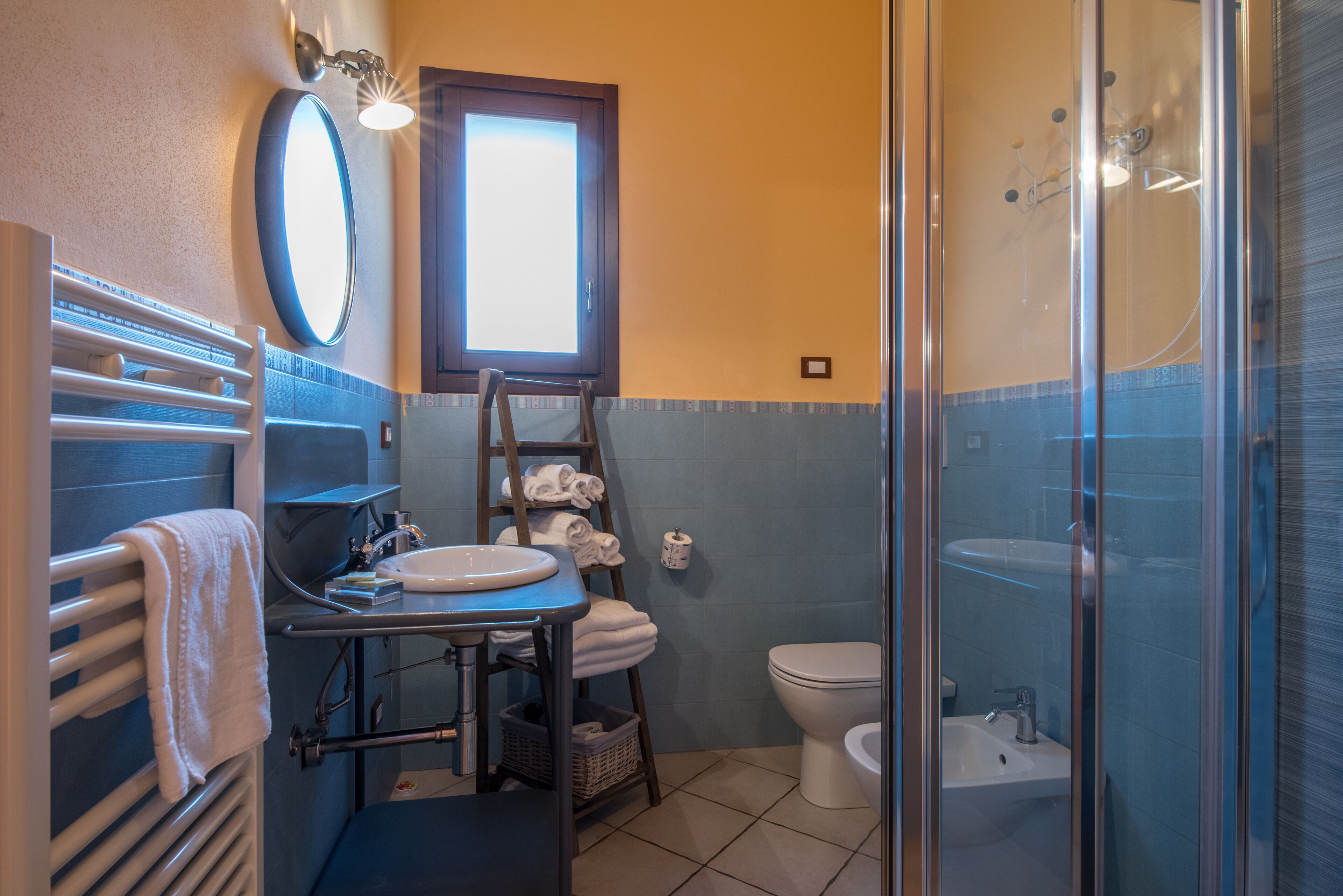 Ein Badezimmer mit Dusche, Waschbecken, Toilette, Handtuchhalter und einem Fenster.