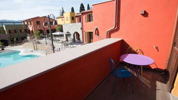 Un balcón con piscina, mobiliario exterior y vistas a edificios coloridos.