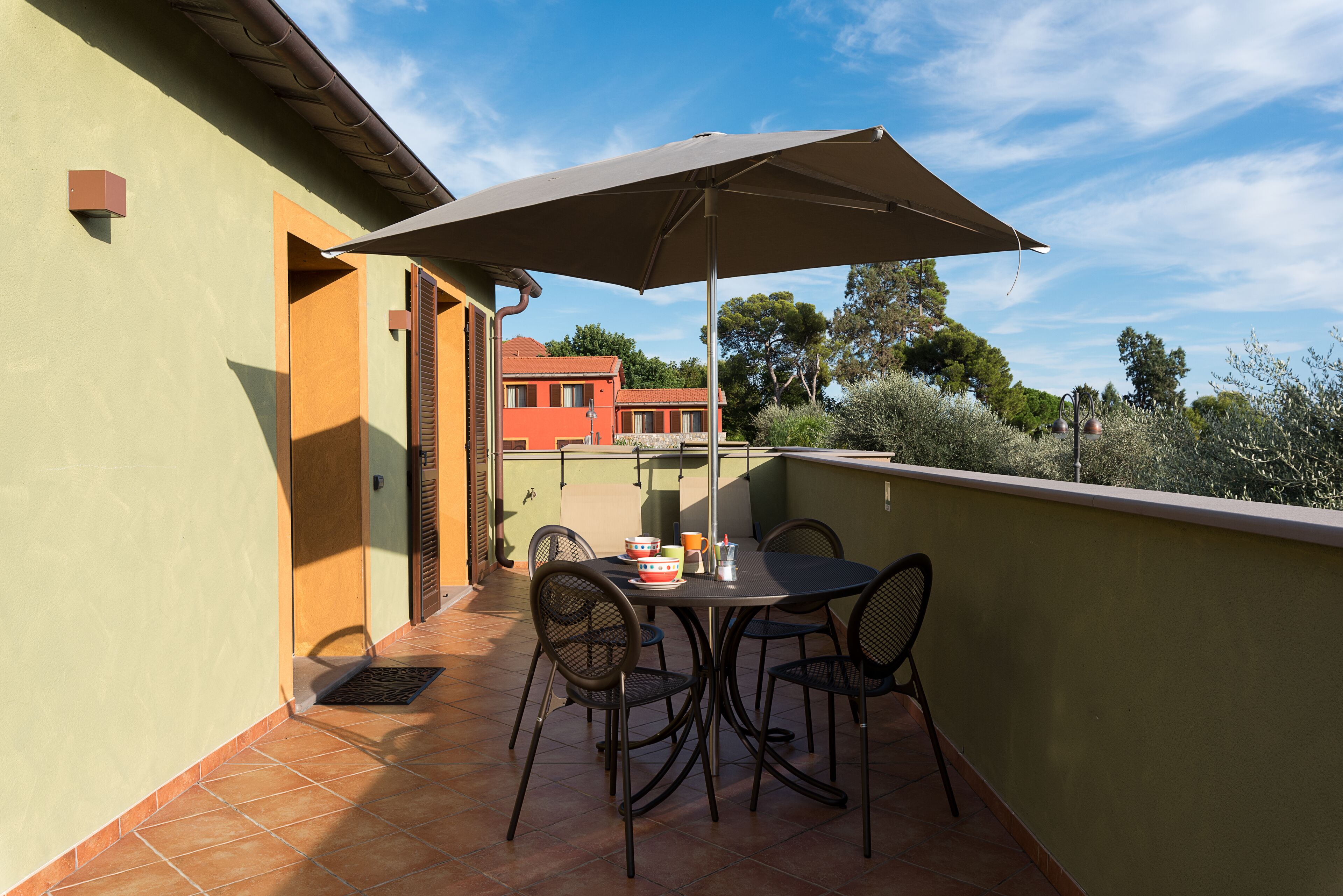 Een balkon met een tafel, stoelen en een parasol.
