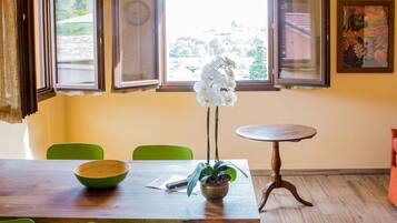 Un coin repas avec une table en bois, des chaises vertes, une orchidée en pot et une petite table ronde.