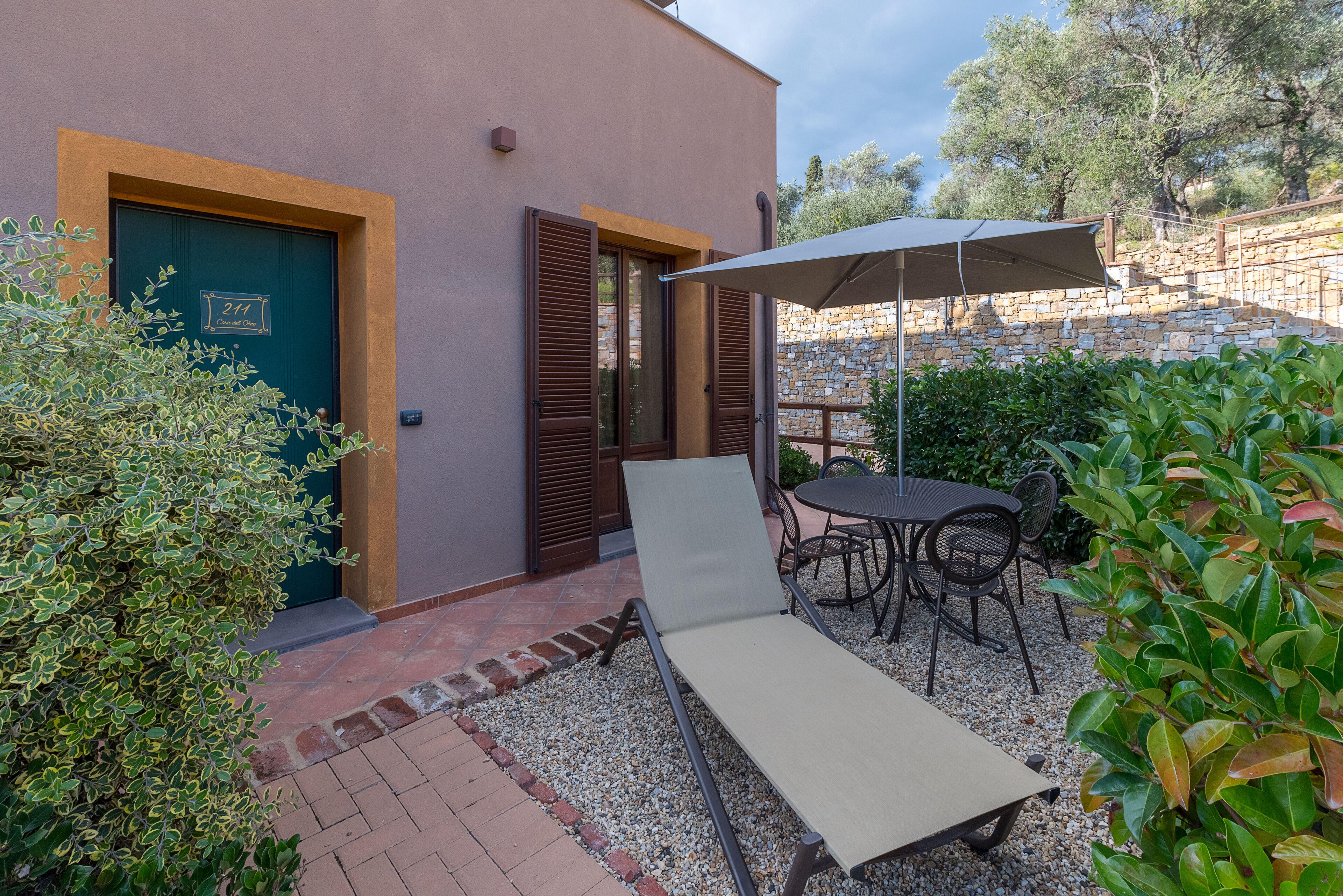A patio with a lounge chair, a table, and an umbrella.