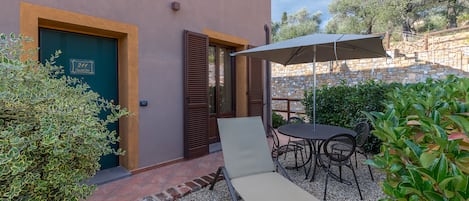 A patio with a lounge chair, a table, and an umbrella.