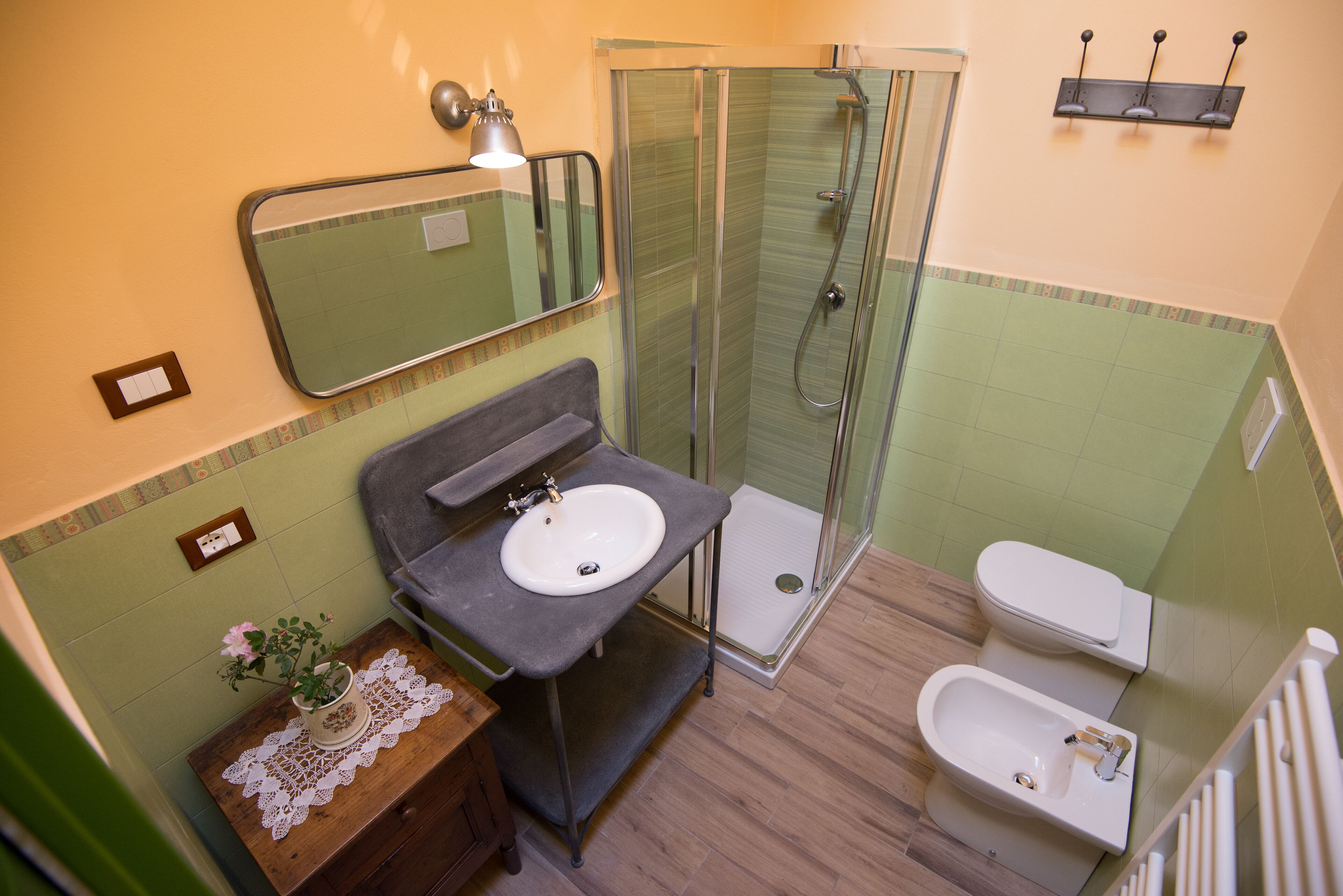 Un baño con lavamanos, espejo, ducha e inodoro.