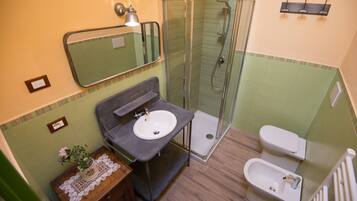 Un baño con lavamanos, espejo, ducha e inodoro.