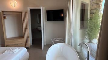 Un baño moderno con una bañera independiente, un espejo grande y un televisor montado en la pared.