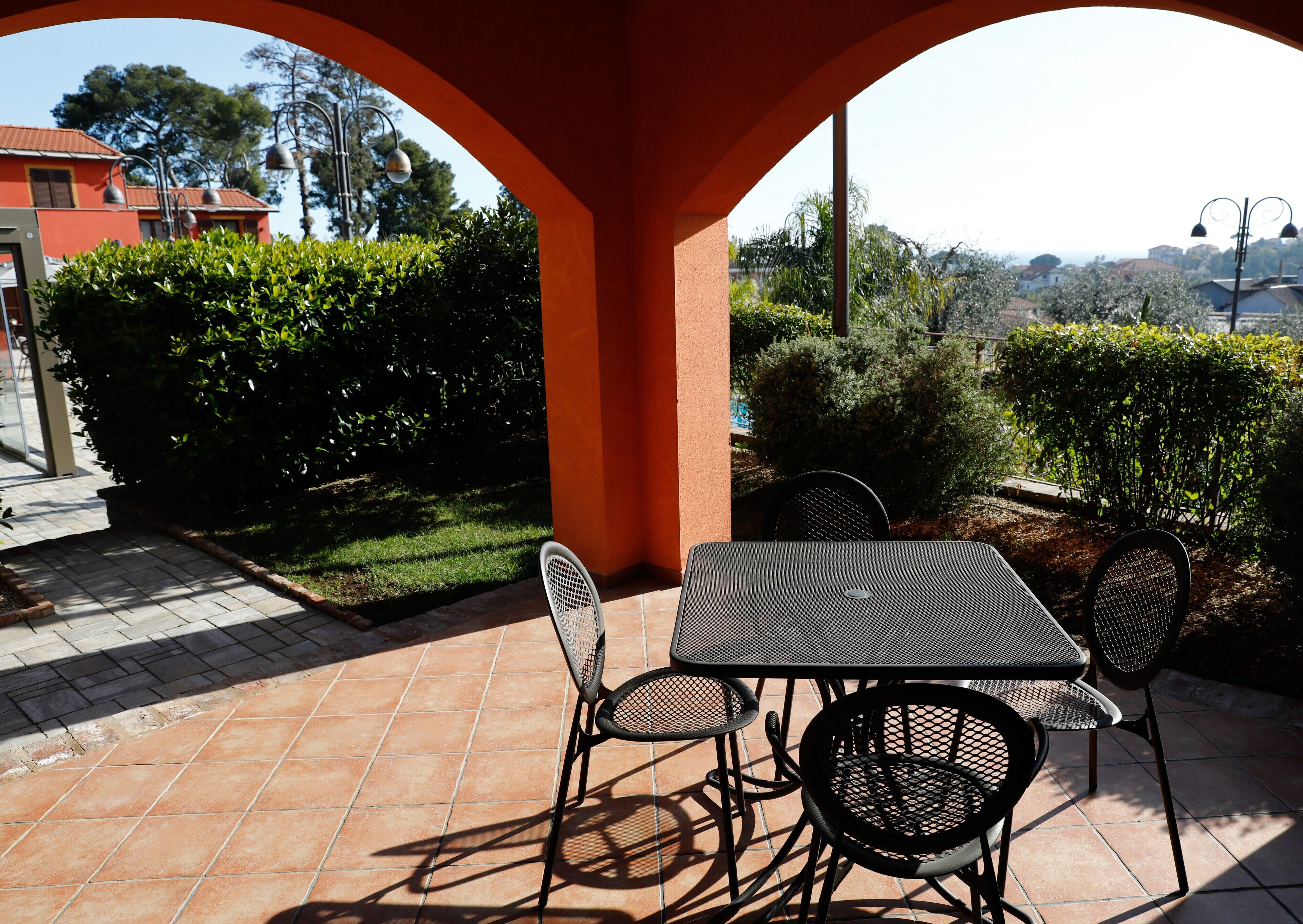 An outdoor patio with a table and chairs, surrounded by greenery and a view of the countryside.