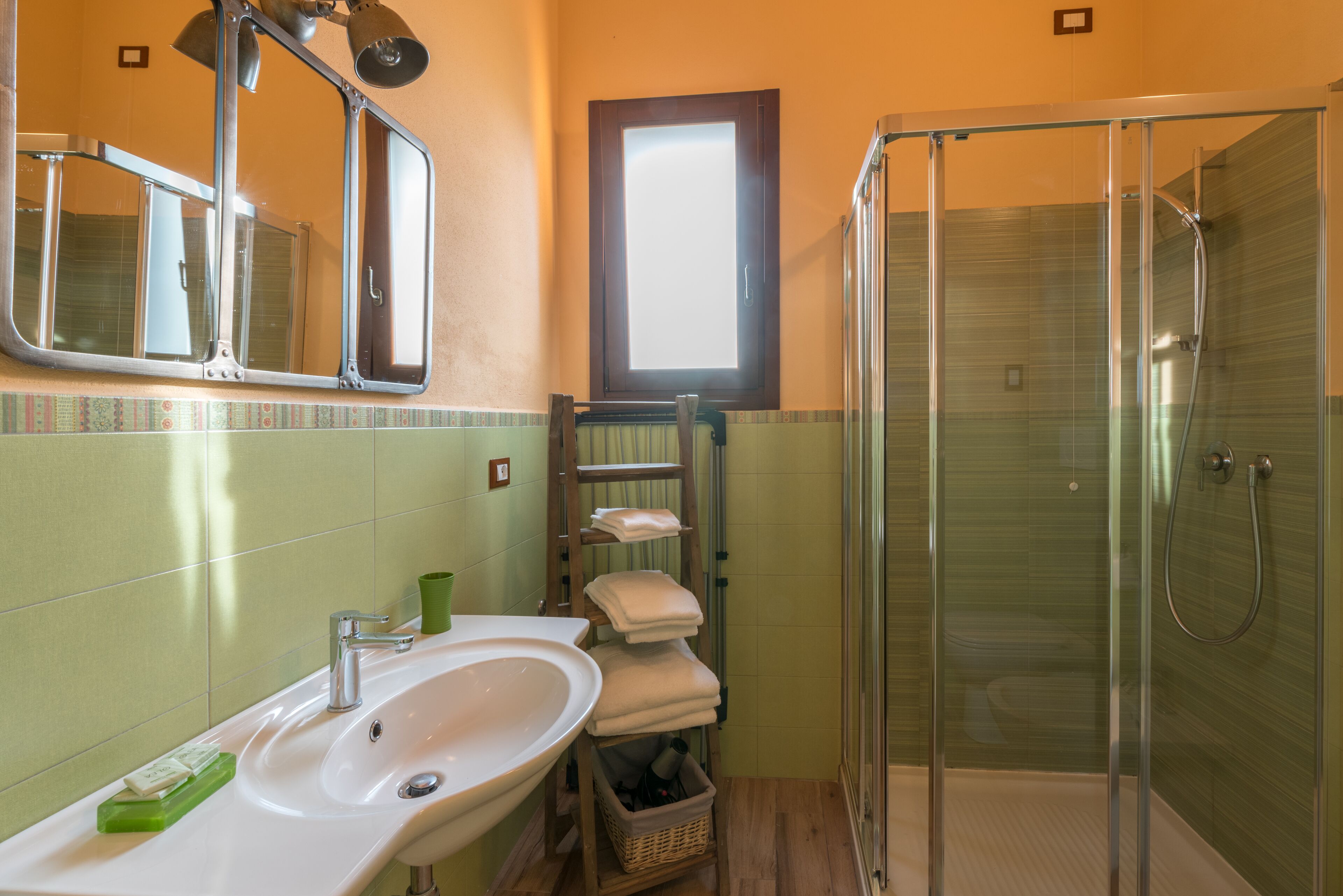 A bathroom with a sink, mirror, towel rack, and glass shower enclosure.