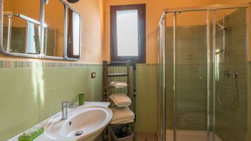 Une salle de bain équipée d’un lavabo, d’un miroir, d’un porte-serviettes et d’une douche à parois en verre.