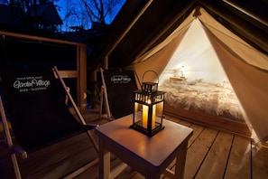 A cozy tented accommodation with a bed, a lantern, and a chair. - Garden Village Bled (Bled)
