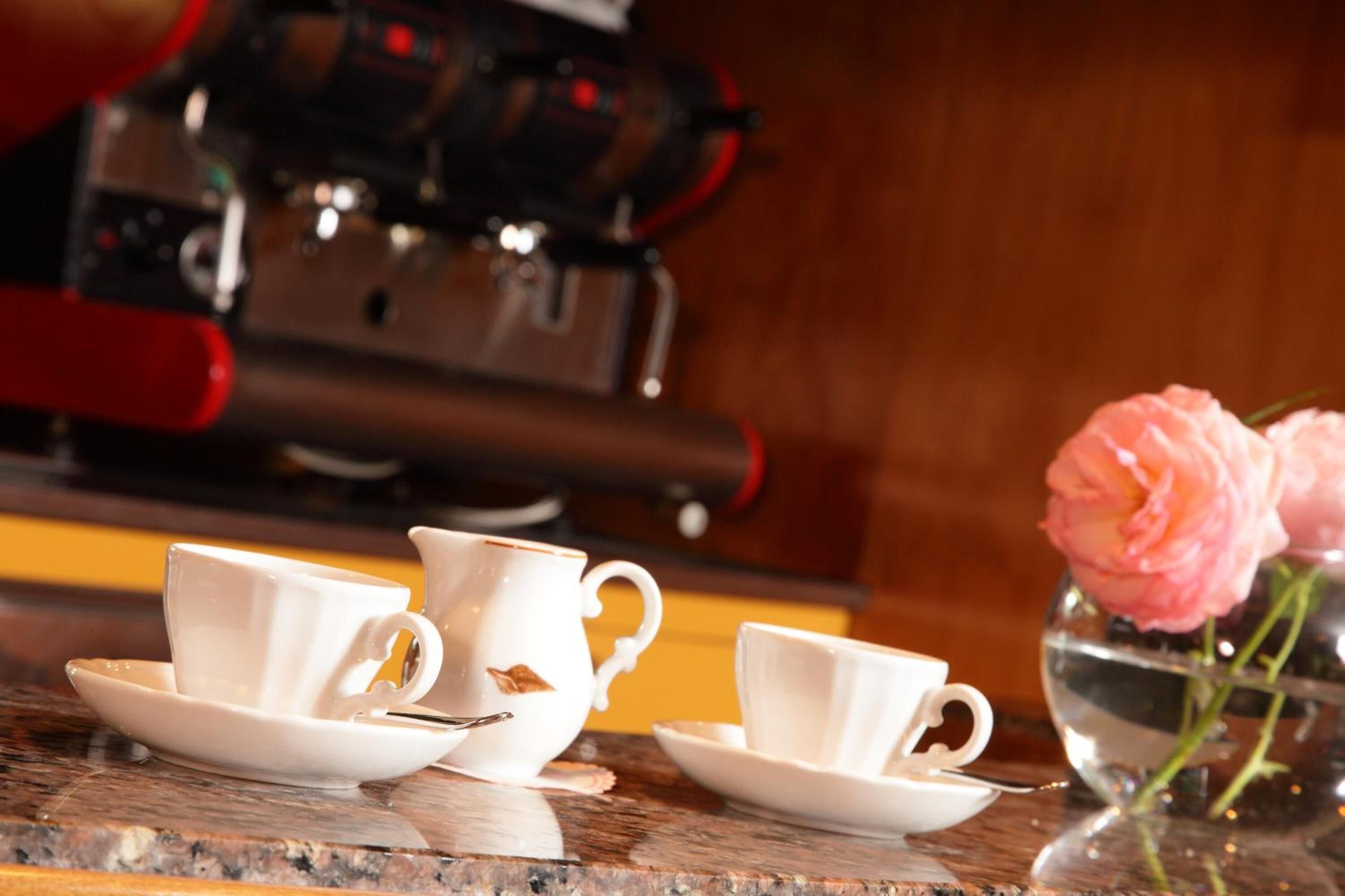 Una cafetera y dos tazas blancas sobre una mesa de madera.