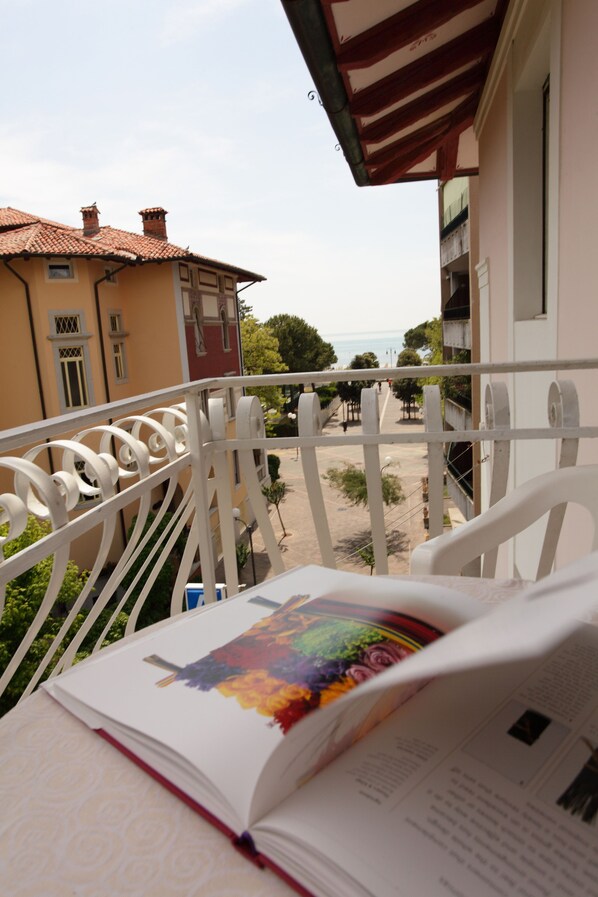 Un balcon avec un livre, une balustrade et une vue sur les bâtiments et la mer.