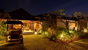 A well-lit building with a covered entrance, a golf cart, and lush greenery. - Ubud Wana Villa (Ubud)
