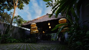 A thatched-roof outdoor area with hanging lamps and a paved walkway. - Ubud Wana Villa (Ubud)