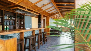 A bar area with wooden beams, a tiled floor, and bar stools. - Hotel The Coast (Pokhara)