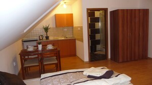 A compact room with a bed, a small kitchenette, a dining table, and a wardrobe. - Apartmány STAR (Bobrovec)