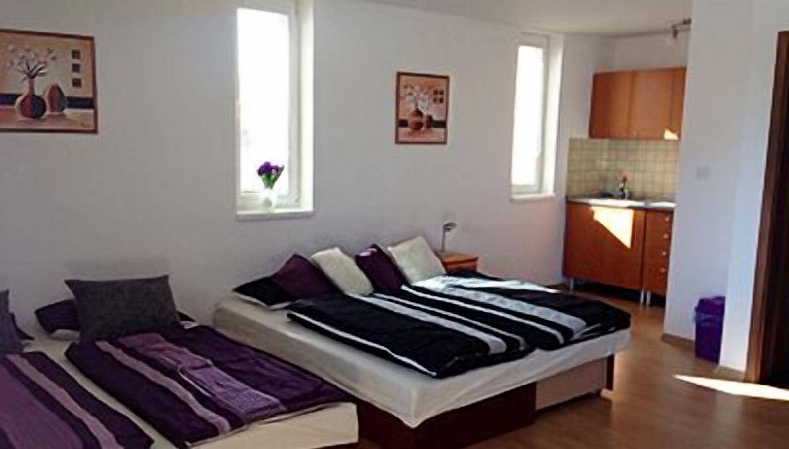 Un dormitorio con cama, mesita de noche y ventana.
