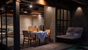 Un espacio al aire libre acogedor con una mesa y sillas, una silla de descanso y una piscina.