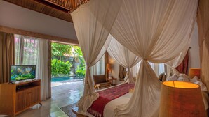Un dormitorio con cama con dosel, un televisor sobre un soporte de madera y vistas a un jardín.