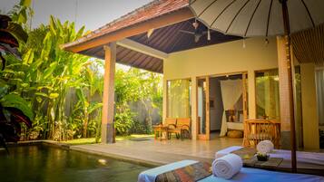 Relax by the serene pool surrounded by lush tropical plants and a comfortable seating area.
