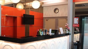 A hotel reception area with a black counter, a flat-screen TV, and a clock on the wall. - Hotel Golden View Nilai (Nilai)