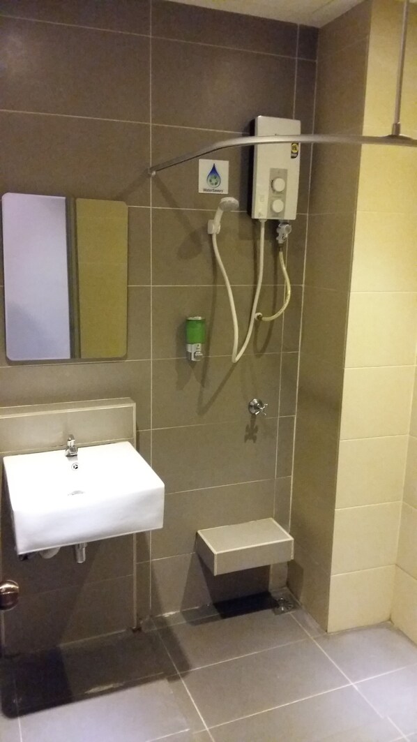 A bathroom with a white sink, a small toilet, and a shower with a control panel. - Hotel Golden View Nilai (Nilai)