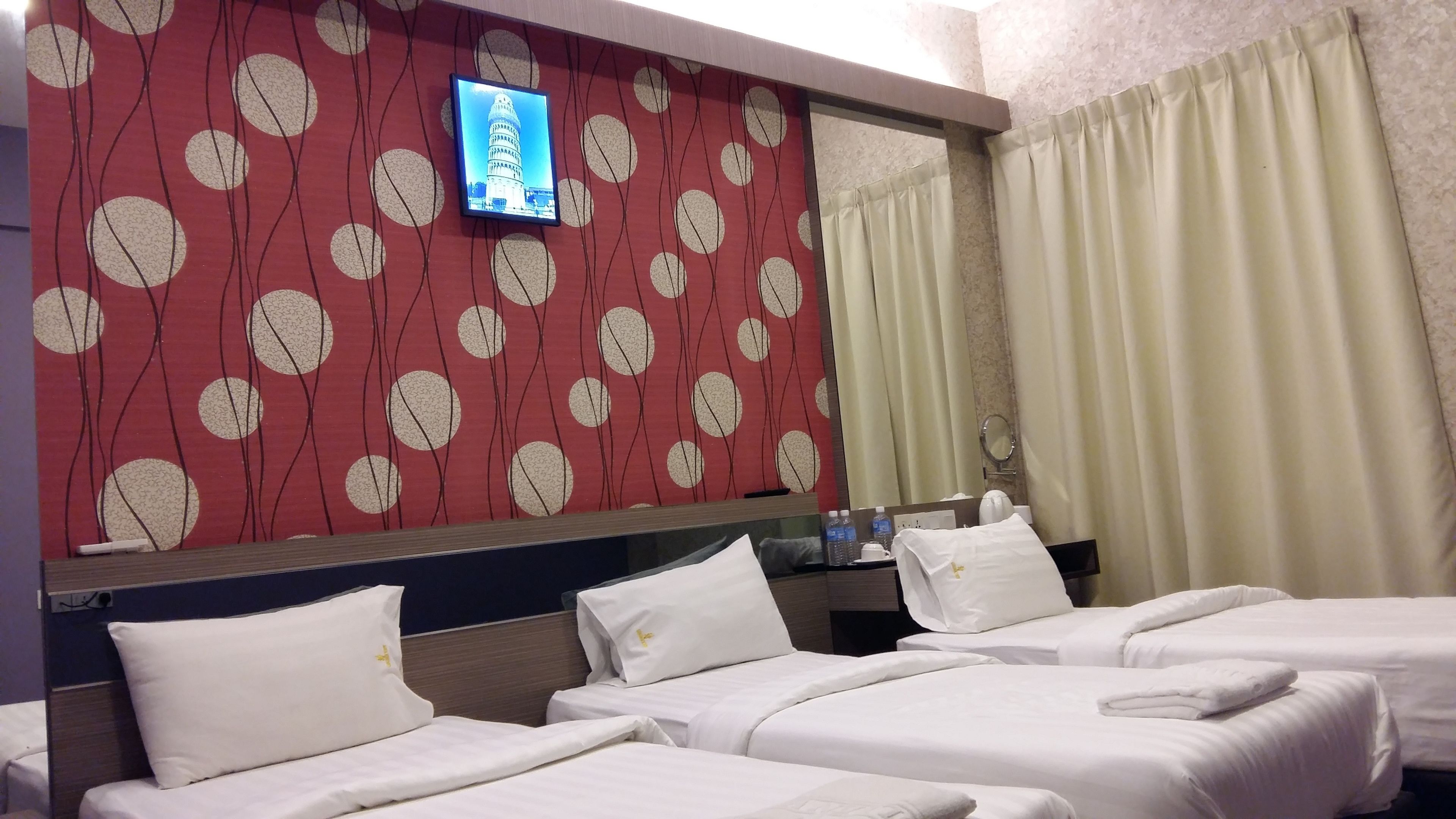 Quarto de hotel com duas camas, televisão fixada na parede e espelho sobre a cama.