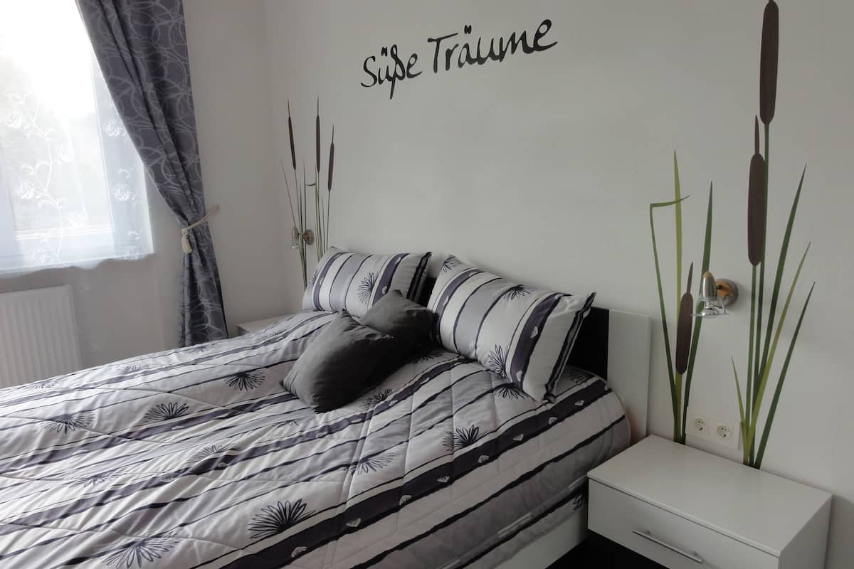 Une chambre à coucher avec un lit, une table de chevet et une lampe fixée au mur.