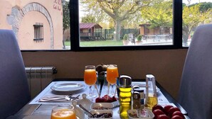 Una mesa de desayuno con vista a un árbol y edificios, incluyendo un letrero que dice "R.R. Cantina Restaurant".