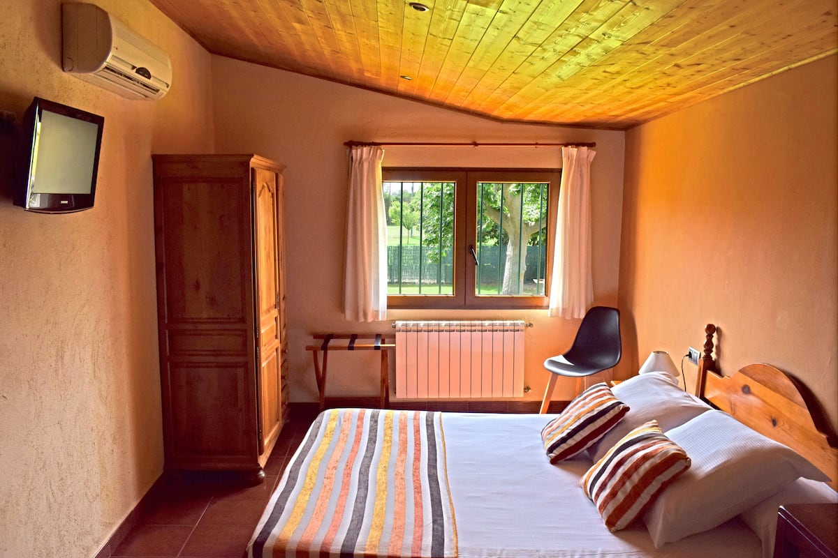 A bedroom with a bed, a desk, a chair, a television, and a wardrobe.