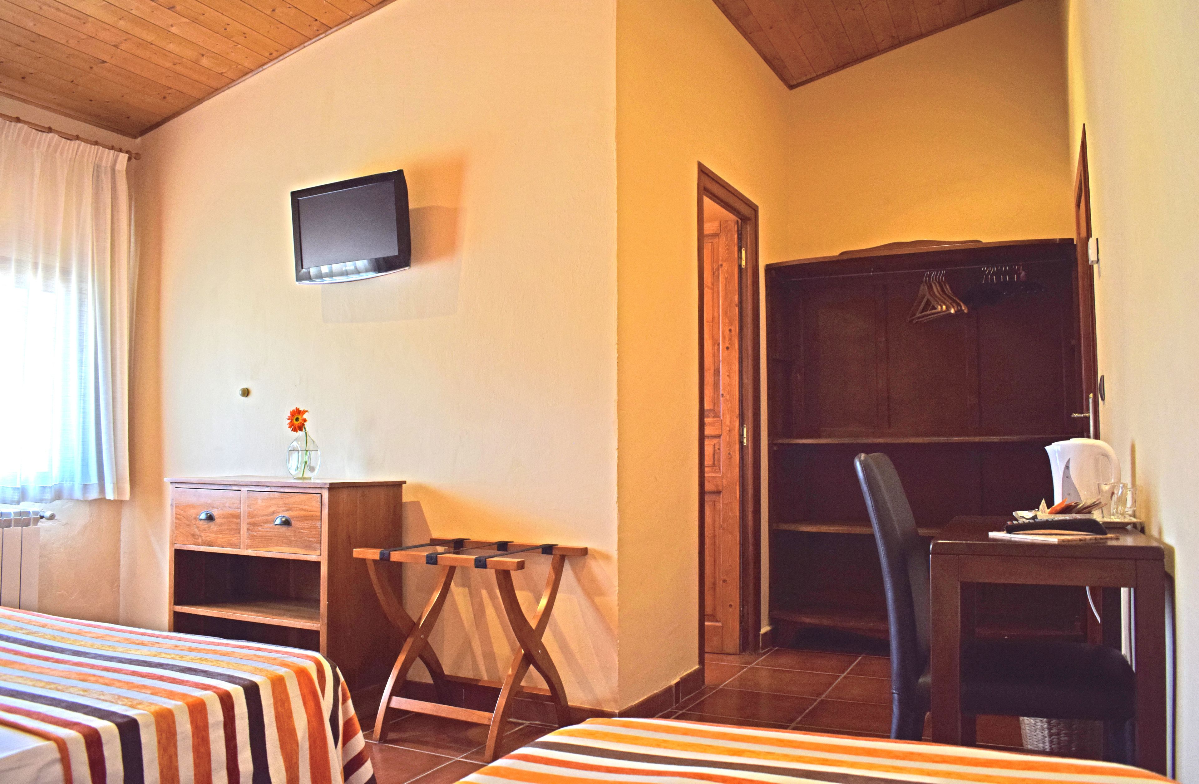 A hotel room with a bed, a desk, a chair, a television, and a wardrobe.