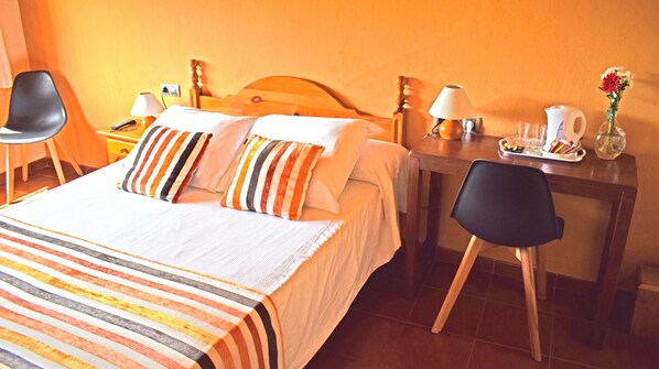 Una habitación de hotel con cama, mesitas de noche, un escritorio y una silla.