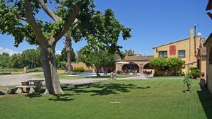 Un patio con césped, un árbol grande y un edificio con techo de tejas.