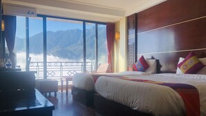 Een hotelkamer met een groot bed, een bureau en uitzicht op bergen.